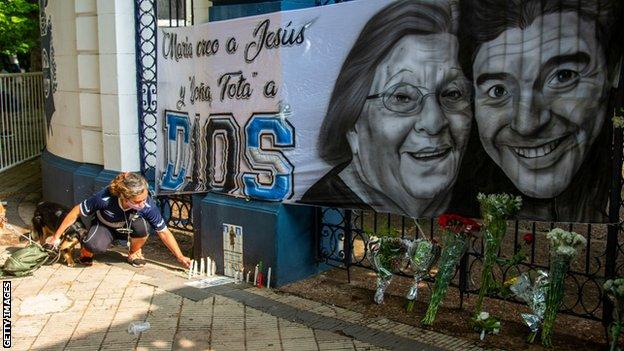 A woman lights a candle at a tribute in La Plata
