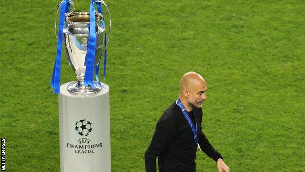 Pep Guardiola walks past the Champions League trophy
