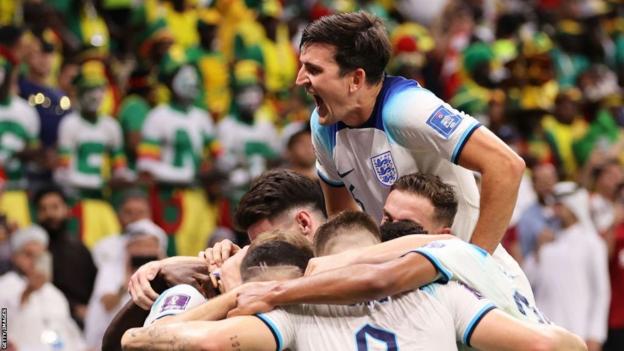 Harry Maguire jumps on top of his team-mates as they celebrate a goal against Senegal