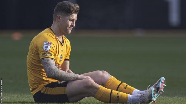 James Clarke nursing his injury during Newport's game with Mansfield