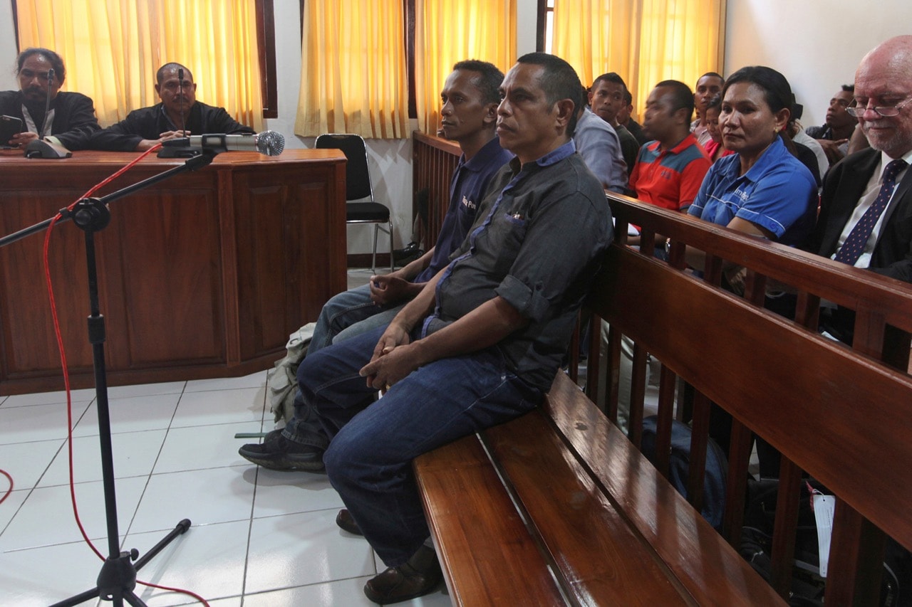 Journalists Lourenco Martins, center front, and Raimundos Oki, center rear, sit on the dock during their trial at a court in Dili, East Timor, 1 June 2017, AP Photo/Kandhi Barnez