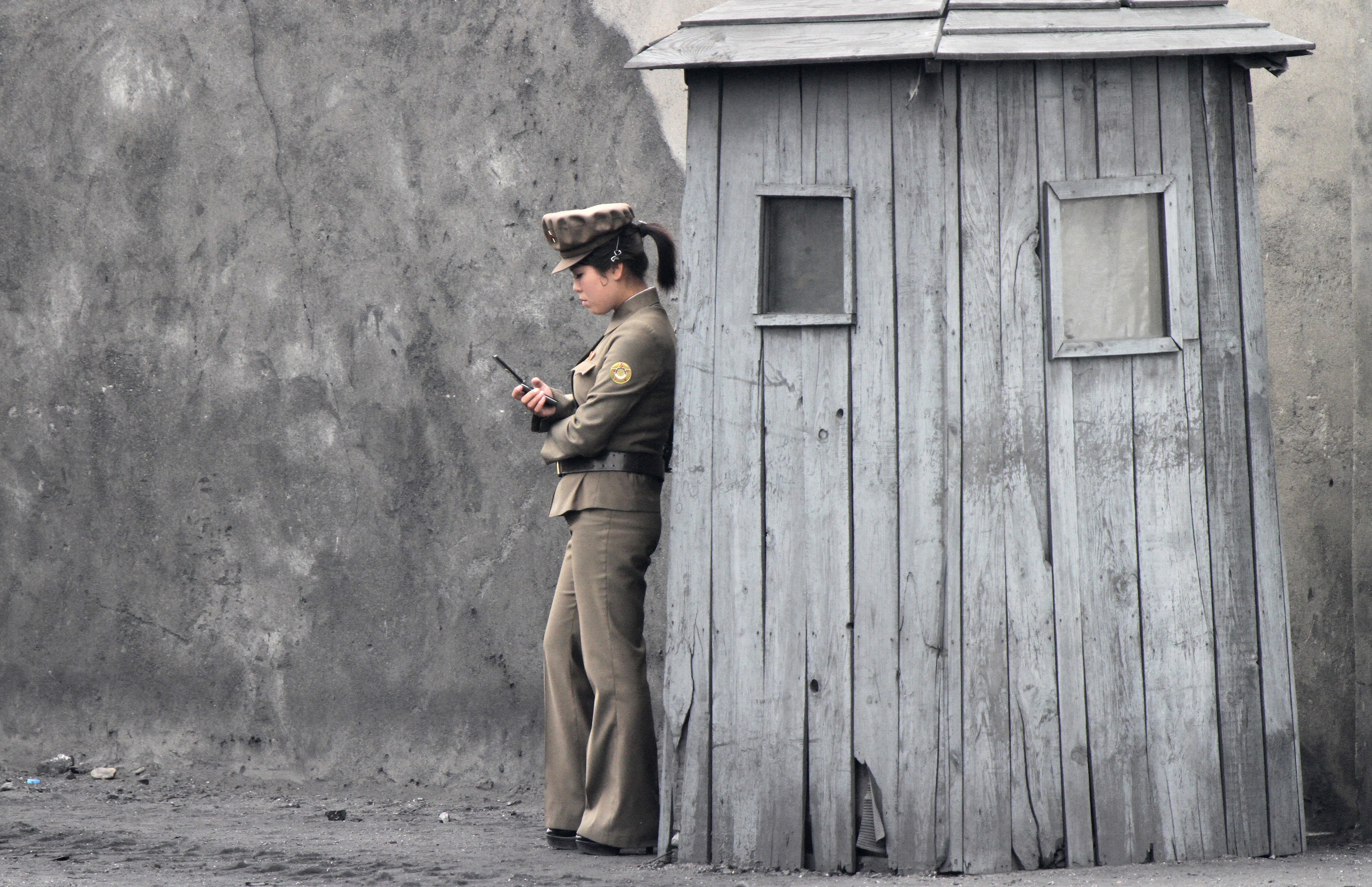 A North Korean soldier uses her mobile phone next to a sentry near the town of Sinuiju, by the border with China, 1 June 2014, REUTERS/Jacky Chen