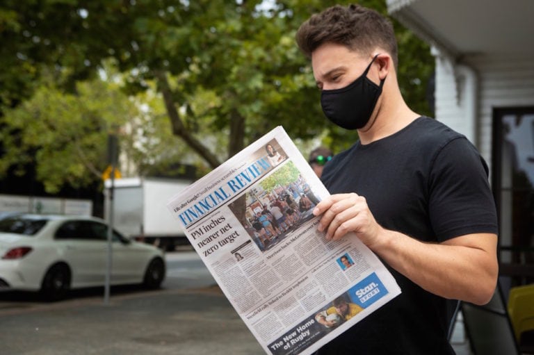 A man wearing a mask reads a newspaper, in Perth, Australia, 2 February 2021, Matt Jelonek/Getty Images