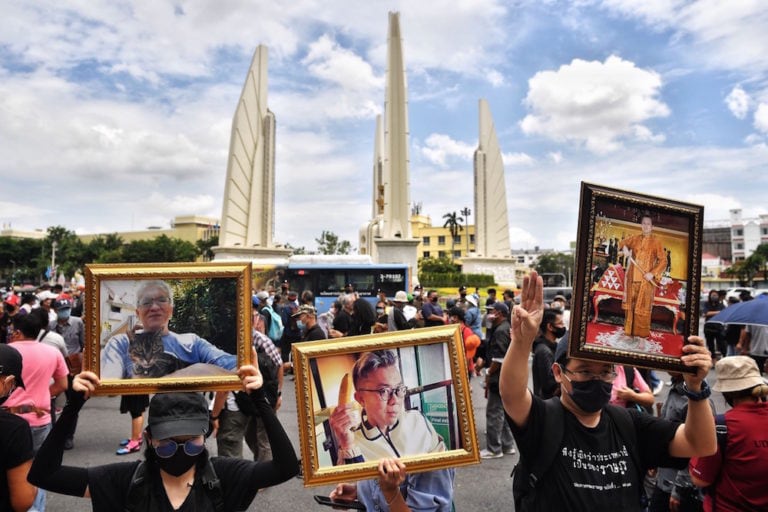 Anti-government protesters hold photos of political commentator Pavin Chachavalpongpun (C) and ex-Reuters journalist Andrew MacGregor Marshall at a rally in Bangkok, 16 August 2020, LILLIAN SUWANRUMPHA/AFP via Getty Images