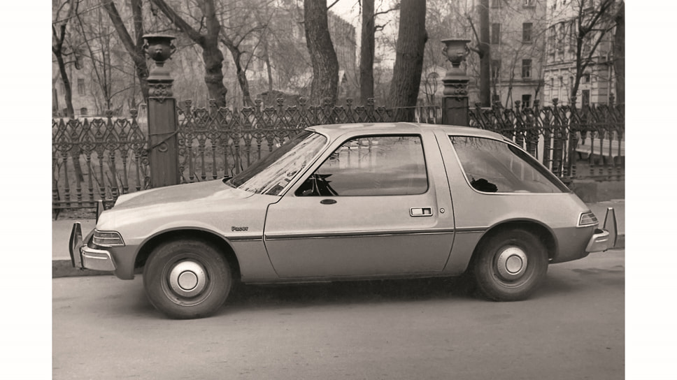 Американский AMC Pacer — компактный автомобиль, выпускавшийся American Motors Corporation с 1975 по 1980 год. Номерной знак «76-40 мму» относится к частной серии и мог быть выдан как в 1975-м, так и в 1976 году, то есть в данном случае на новую машину. Фотография сделана 21 апреля 1977 года в Брюсовом переулке. На заднем плане виден и советский вариант «компактного автомобиля» — ЗАЗ-968 «Запорожец». На тот момент серийная модель