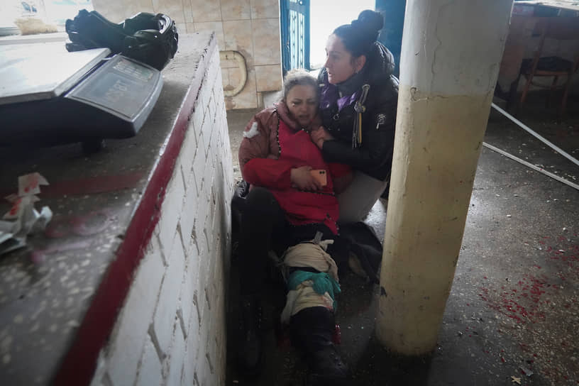 Женщина оказывает первую помощь раненой после обстрела Волчанска 