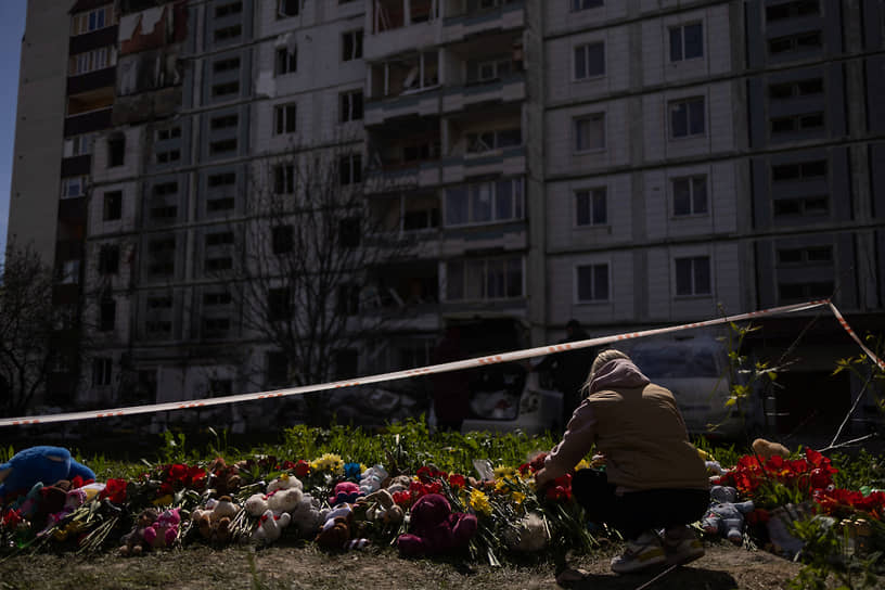 Женщина рядом с пострадавшим из-за ракетного обстрела жилого дома в городе Умань Черкасской области