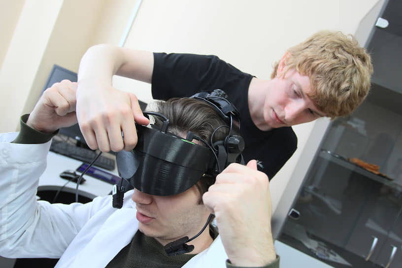 Лаборант надевает на голову испытуемого устройство виртуальной реальности с датчиками на кафедре нейрофизиологии ННГУ