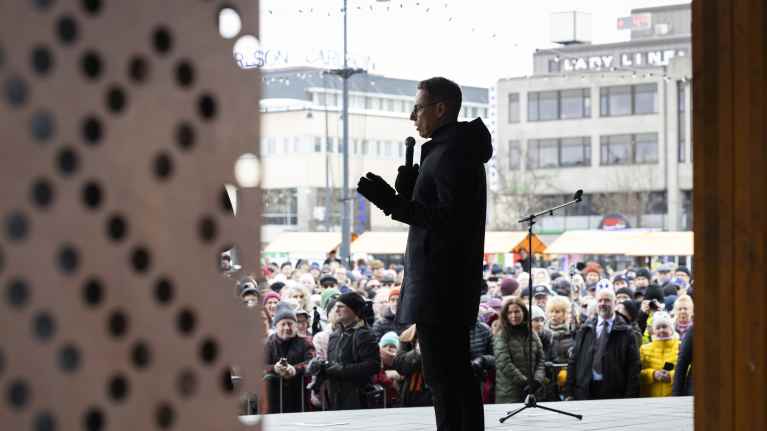 Tasavallan presidentti Alexander Stubb puhuu Joensuun torin lavalla ja taustalla on suuri määrä ihmisiä kuuntelemassa.