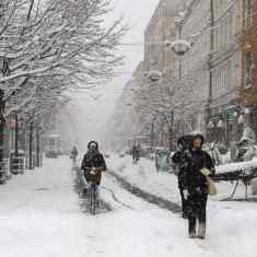 Photo shows people walking and cycling on a snow-covered street in Turku.