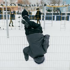 Lapsi roikkuu aidan päällä.