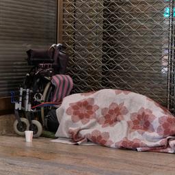 Ein Mensch liegt in der Innenstadt von Köln in einem Schlafsack im Eingang zu einem Geschäft (Archivbild)