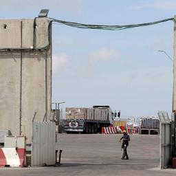Ein bewaffneter Wachposten patrouilliert am Grenzübergang Kerem Shalom, im Hintergrund stehen Lkw mit Hilfslieferungen für den Gazastreifen.