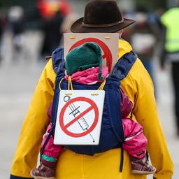 Eine Teilnehmerin einer Protestkundgebung der Initiative "Querdenker" trägt auf dem Cannstatter Wasen ein Schild gegen Impfungen auf ihrem Rücken.