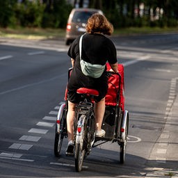 Eine Fahrradfahrerin fährt mit einem Lastenfahrrad auf einem Radweg in Berlin-Friedrichshain.