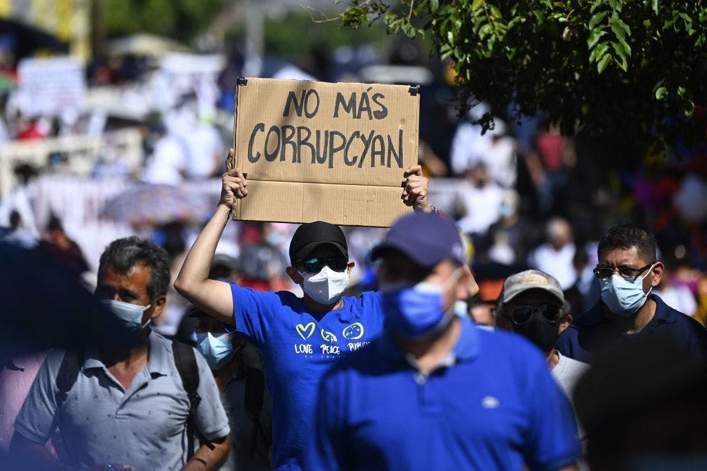 A man holds a sign reading "No more corruption" during a protest in El Salvador.