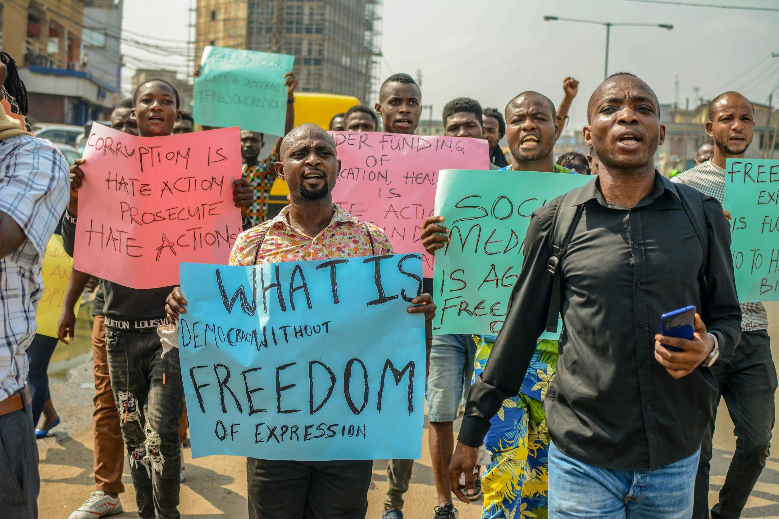 Young activists in Nigeria protesting against the 2019 anti-social media bill; signs read: "what is democracy without freedom of expression" and "corruption is hate action, prosecute hate action"