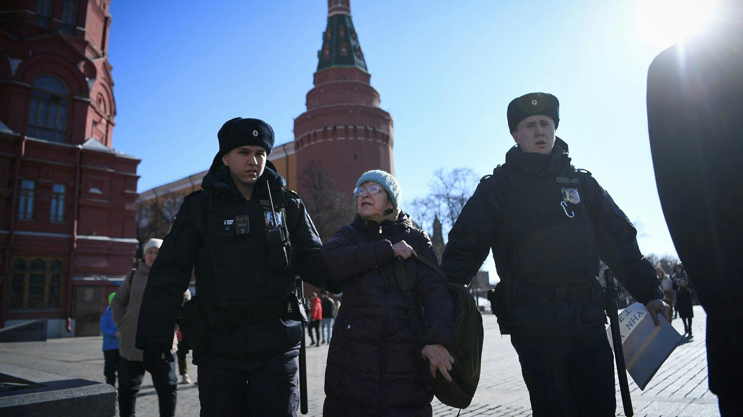 An elderly woman in Moscow is detained and flanked by two police officers as she protests Russia's invasion of Ukraine.