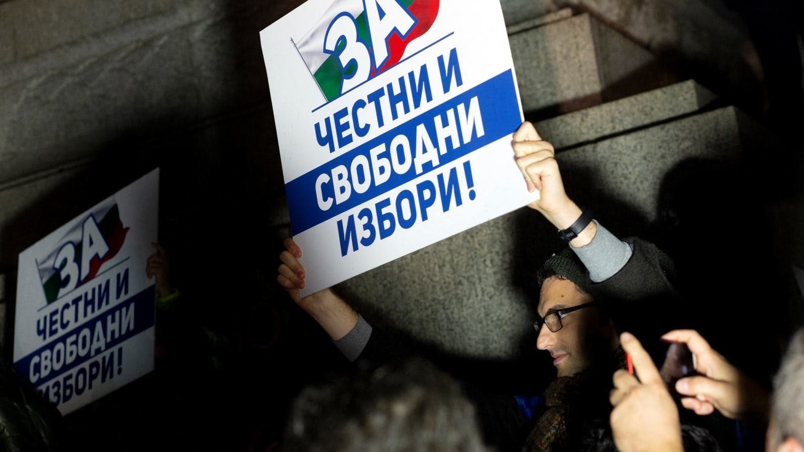 A man holding a protest sign that reads "for honest and free elections" in Sofia, Bulgaria