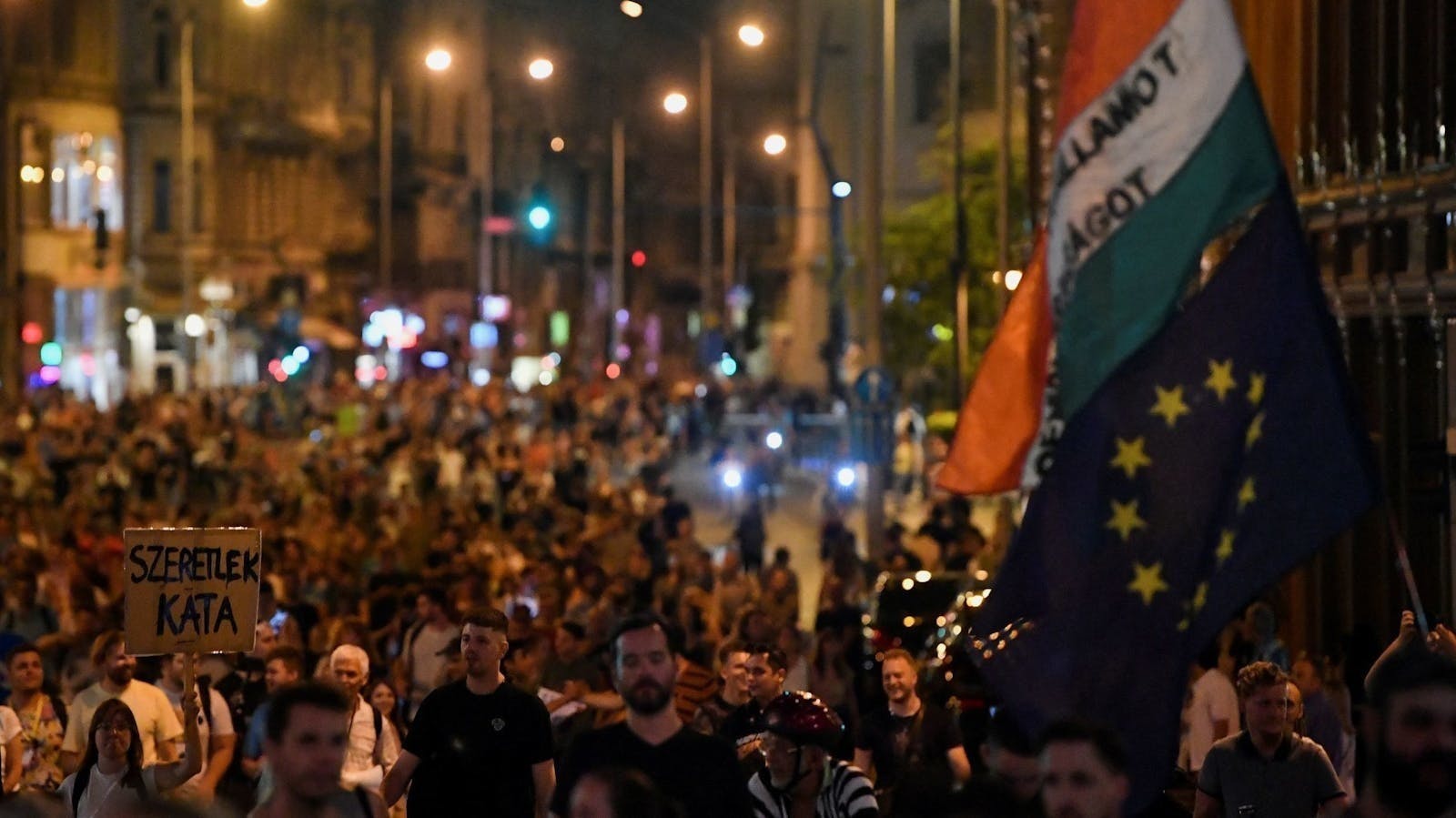 People marching in Budapest at night with Hungarian and EU flags