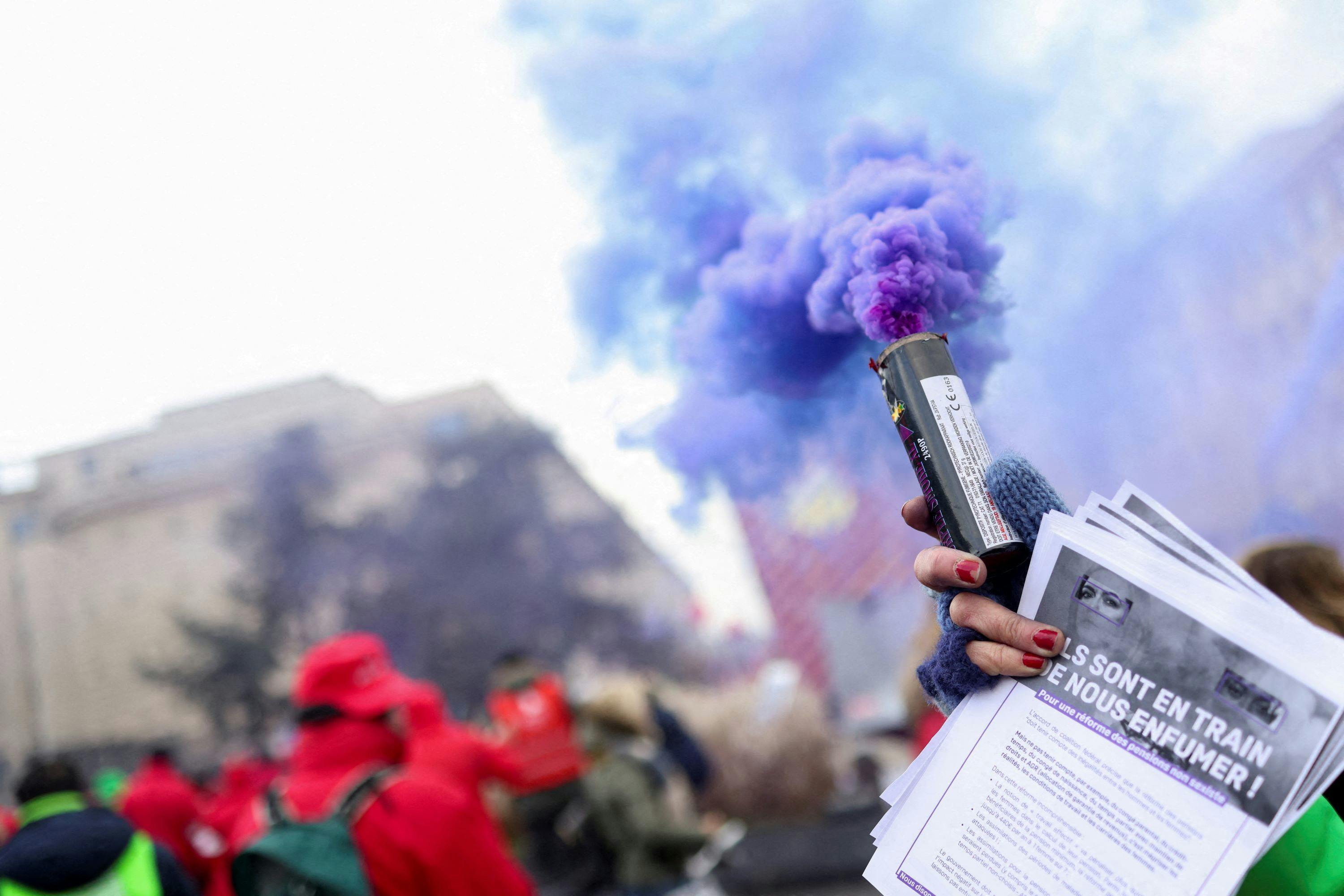 A person holding a smoke grenade takes part in a demonstration against the rising cost of living in Brussels, Belgium