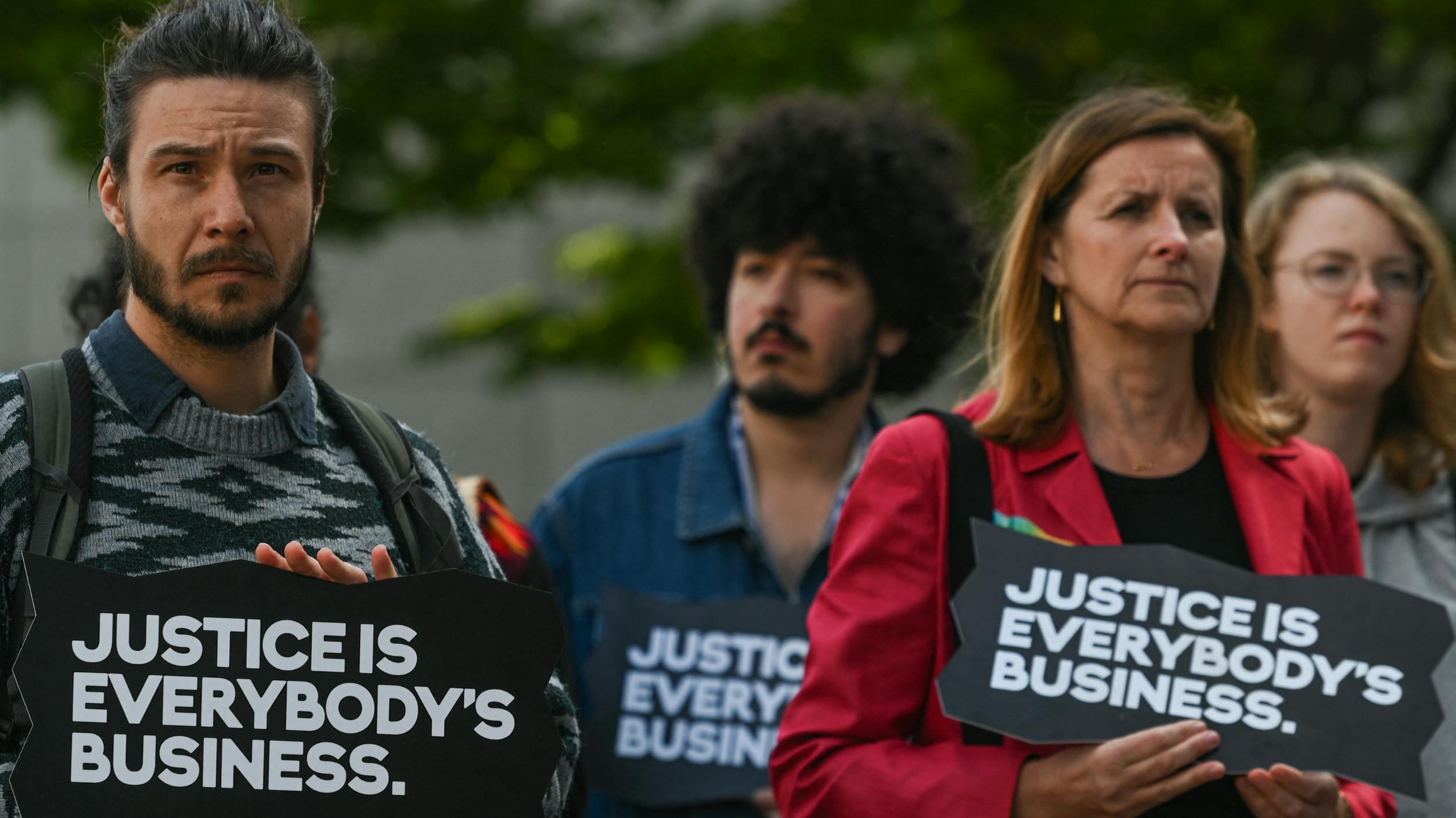 A group of activists holding signs reading 'Justice is Everybody's Business' during a protest