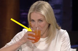 Woman drinking from a glass, sitting at a table, looking at someone off-camera