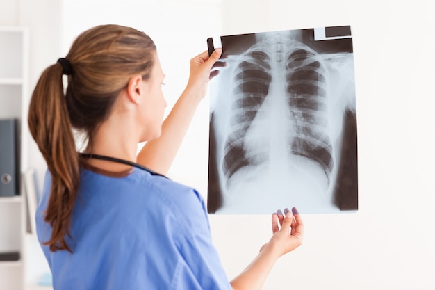 Gorgeous brunette doctor with stethoscope looking at a x-ray