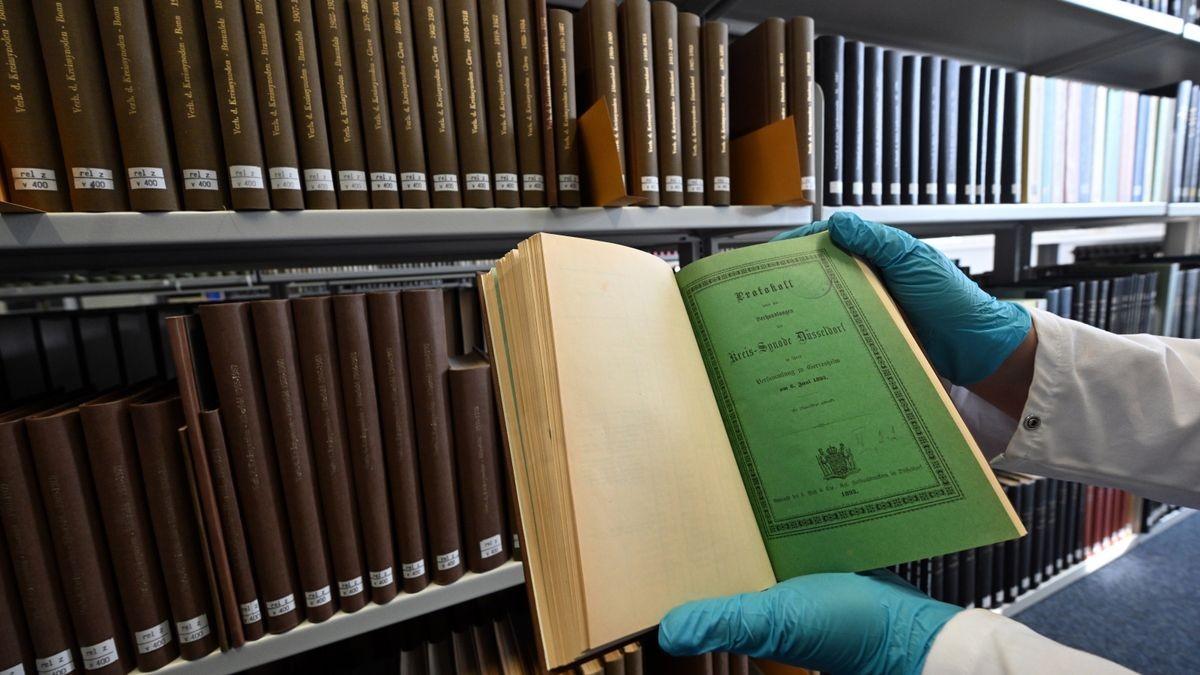 Eine Mitarbeiterin der Universitätsbibliothek Düsseldorf hält ein Buch in den Händen, das möglicherweise mit Arsen belastet ist. Vor allem das intensive „Schweinfurter Grün“ steht im Fokus - ein Pigment, das im 19. Jahrhundert zur Färbung von Einbänden benutzt wurde.