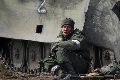 Военнослужащий российской армии сидит рядом с телом военнослужащего, погибшего в ходе боевых действий за город Мариуполь, Украина, 31 марта 2022 года. Фото: Reuters