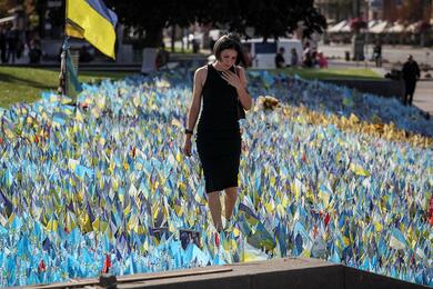 Женщина стоит внутри импровизированного мемориала с украинскими флагами на которых написаны имена погибших на войне военнослужащих на площади Независимости, в Киеве, Украина, 26 сентября 2023 года. Фото: Reuters