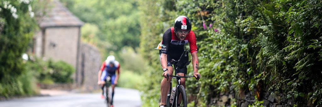 Athletes biking behind each other through nature surrounded of green fields in Bolton at IRONMAN UK