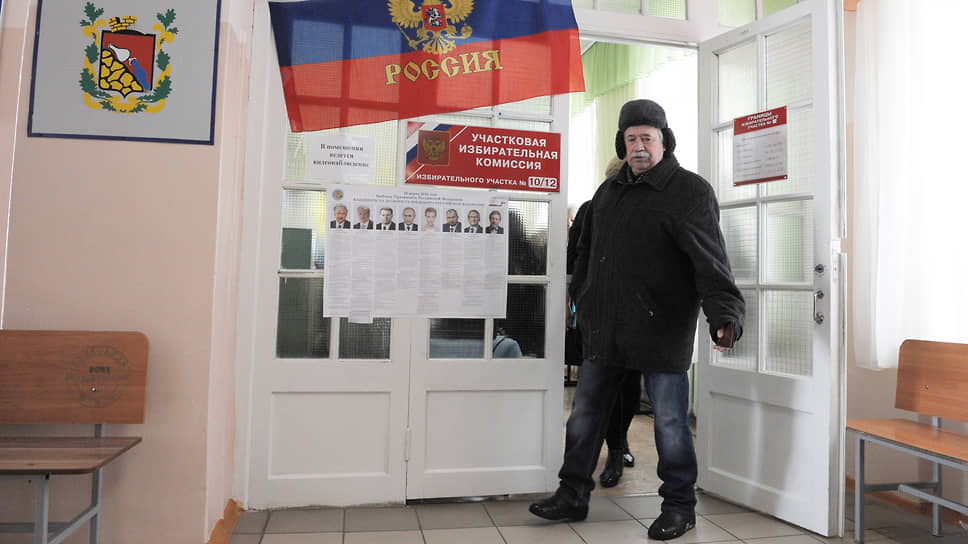 Мужчина на избирательном участке на фоне предвыборных агитматериалов. Март, 2018 год