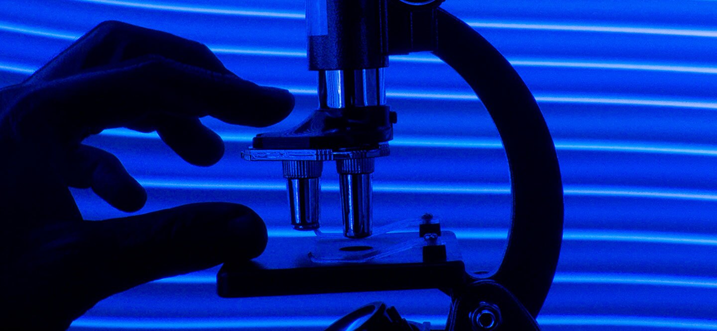 A close-up view of a microscope and a hand