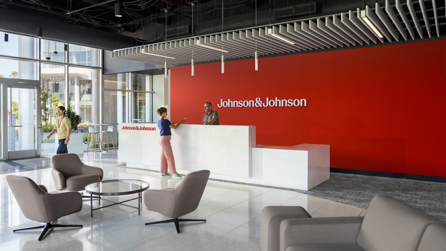 A rendering of a Johnson & Johnson lobby with a red feature-wall displaying the new J&J logo 