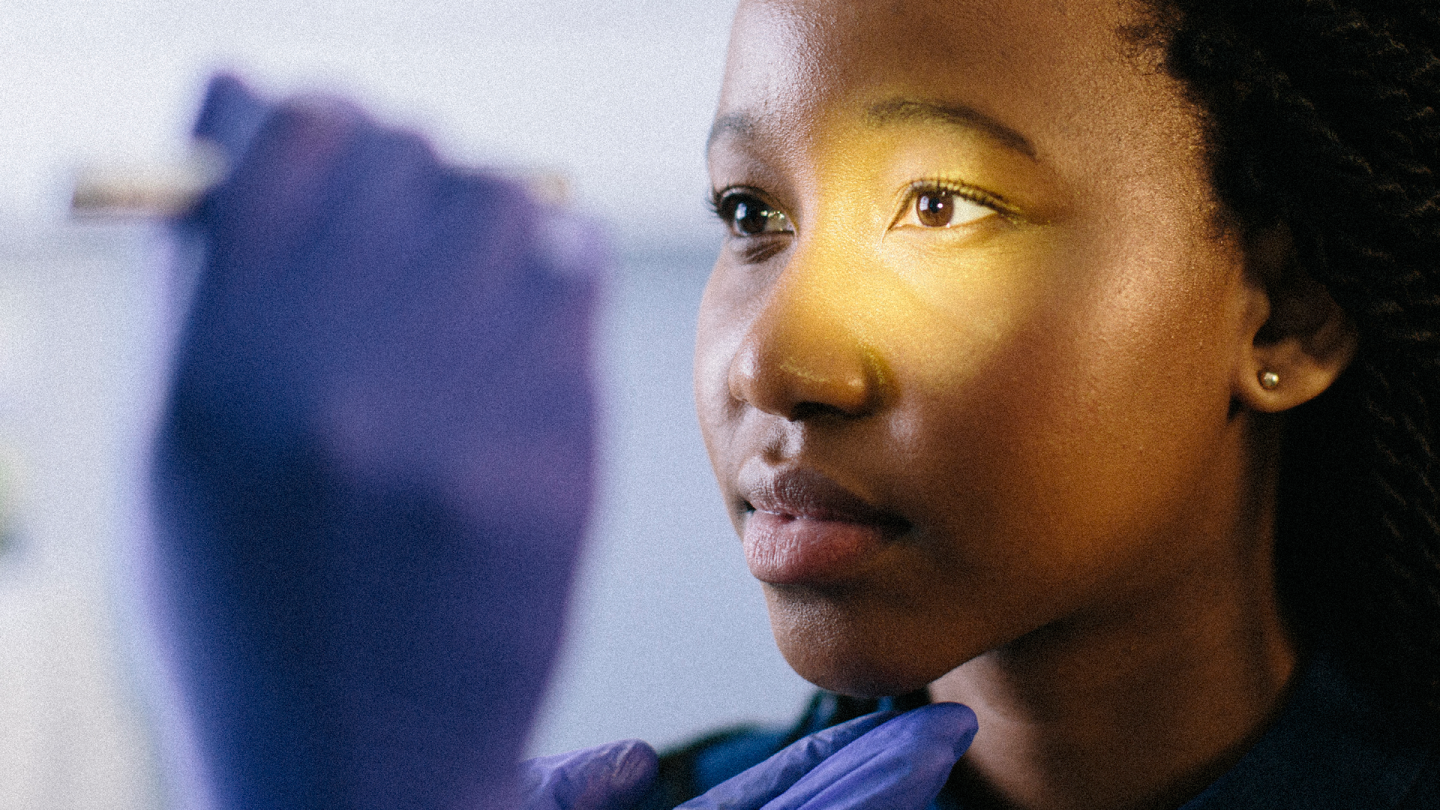 Close-up of a woman with low vision receiving an eye exam exam with a doctor shining light into her left eye