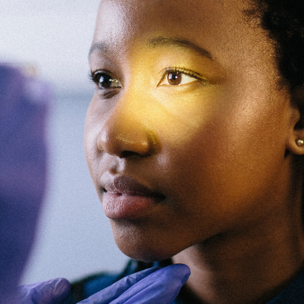 Close-up of a woman with low vision receiving an eye exam exam with a doctor shining light into her left eye