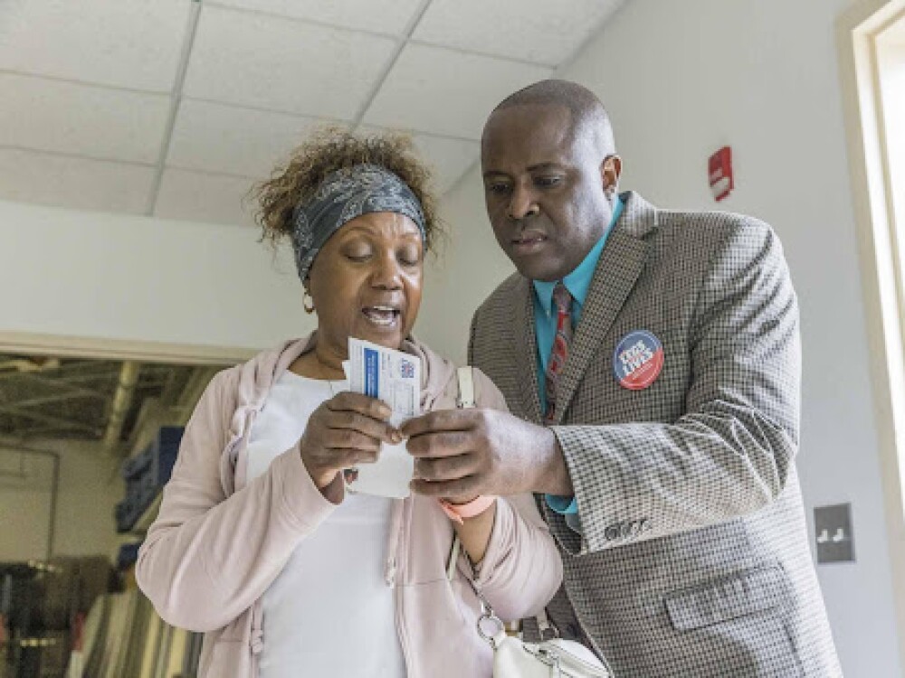 Dr. Richard Brown standing next to a woman looking at a voting pamphlet 