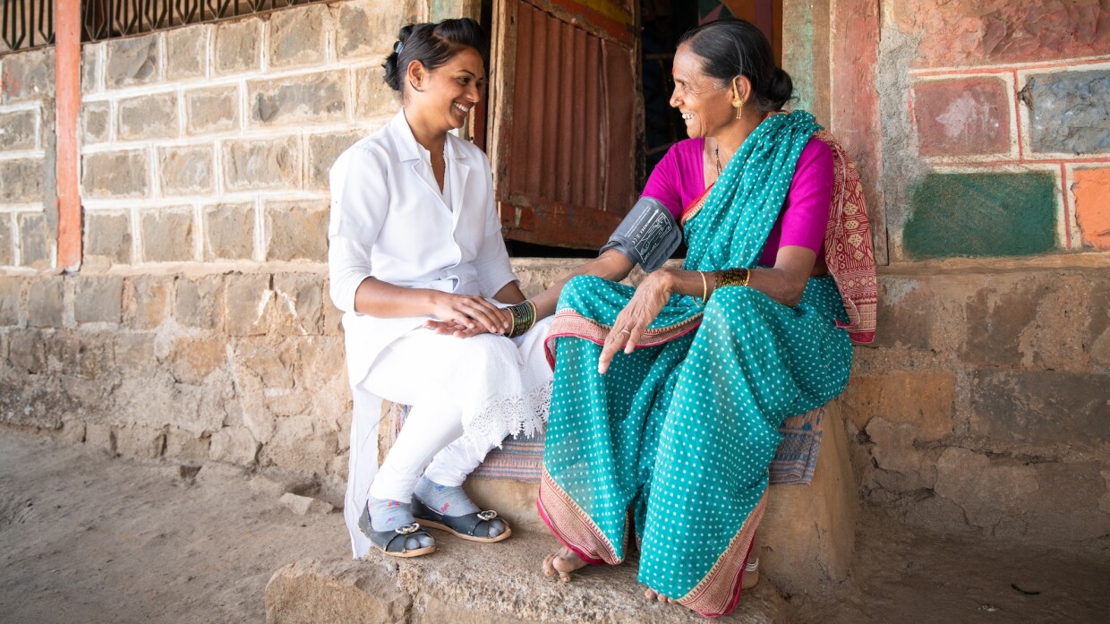 Arti Gajanan Modshe speaking wither her patient Chandrabai Pandurang Sankpal in front of a house 