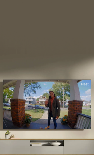 A TV in a living room showing a delivery person standing on a stoop waving to the doorbell camera.