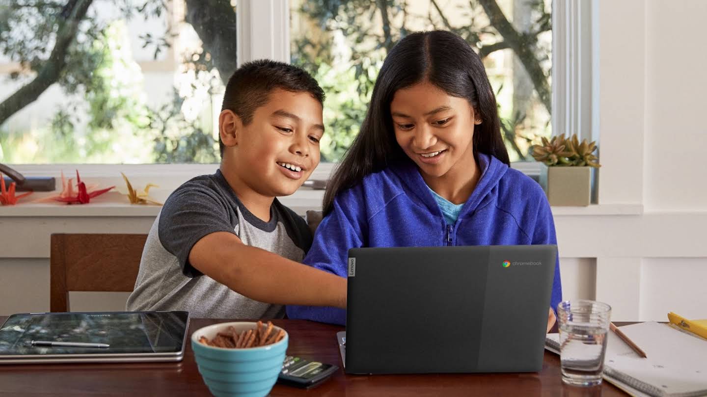 'n Jong seun en dogter werk saam by die huis voor 'n Chromebook-skootrekenaar.