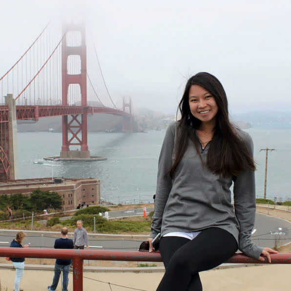 Woman smiling in front of the Golden Gate Bridge.