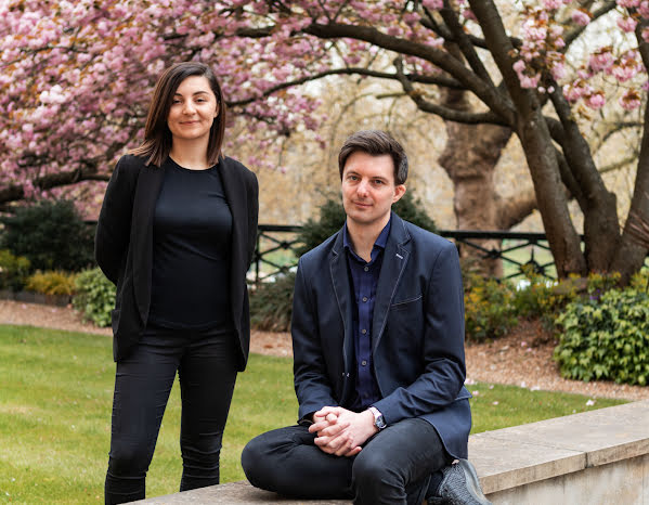 Man and woman posed outside and looking at the camera.