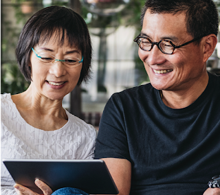 Man and woman sitting on a couch laughing at something they’re watching on an Android tablet