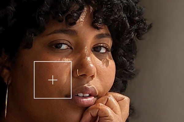 A Black woman looking into the camera with a plus tag hovering over her skin color, illustrating the Monk Skin Tone Scale