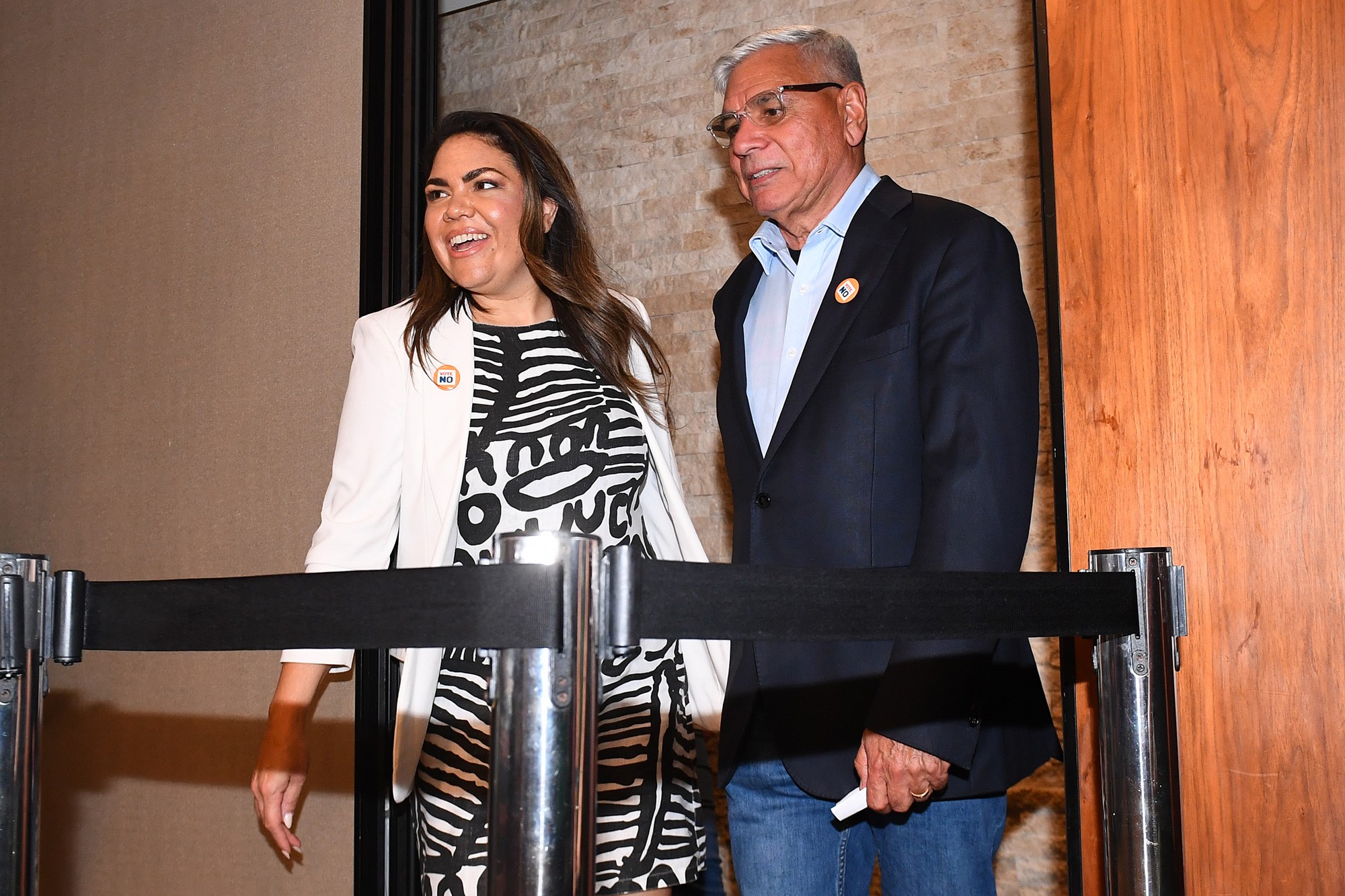 A woman and man walk side by side into a room.