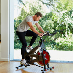 Full length of man working out on exercise bike at home