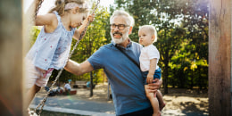 Grandfather Having Fun With Grandchildren On Swings