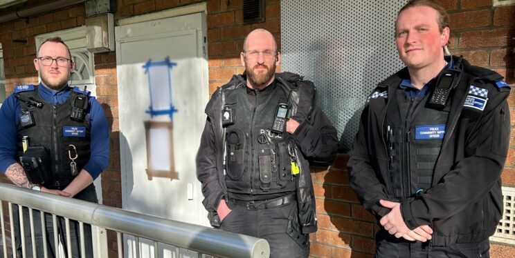Three police officers in uniform in front of the flat that has been made subject of the closure order.