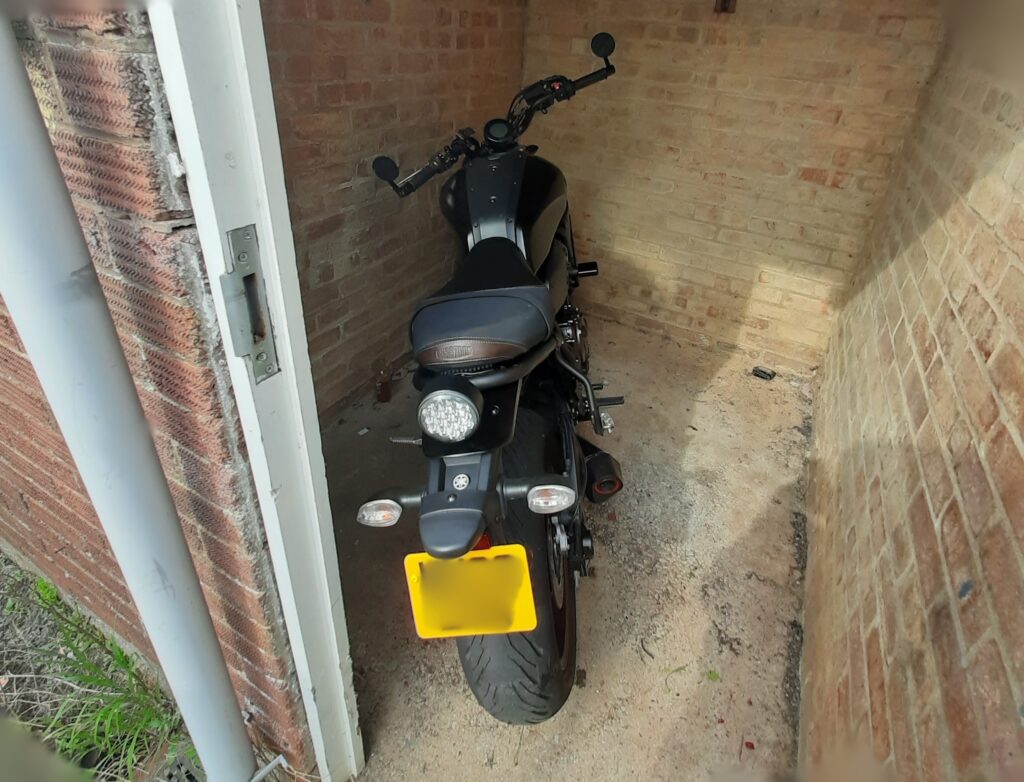 Black motorbike parked in a small bricked up area outside